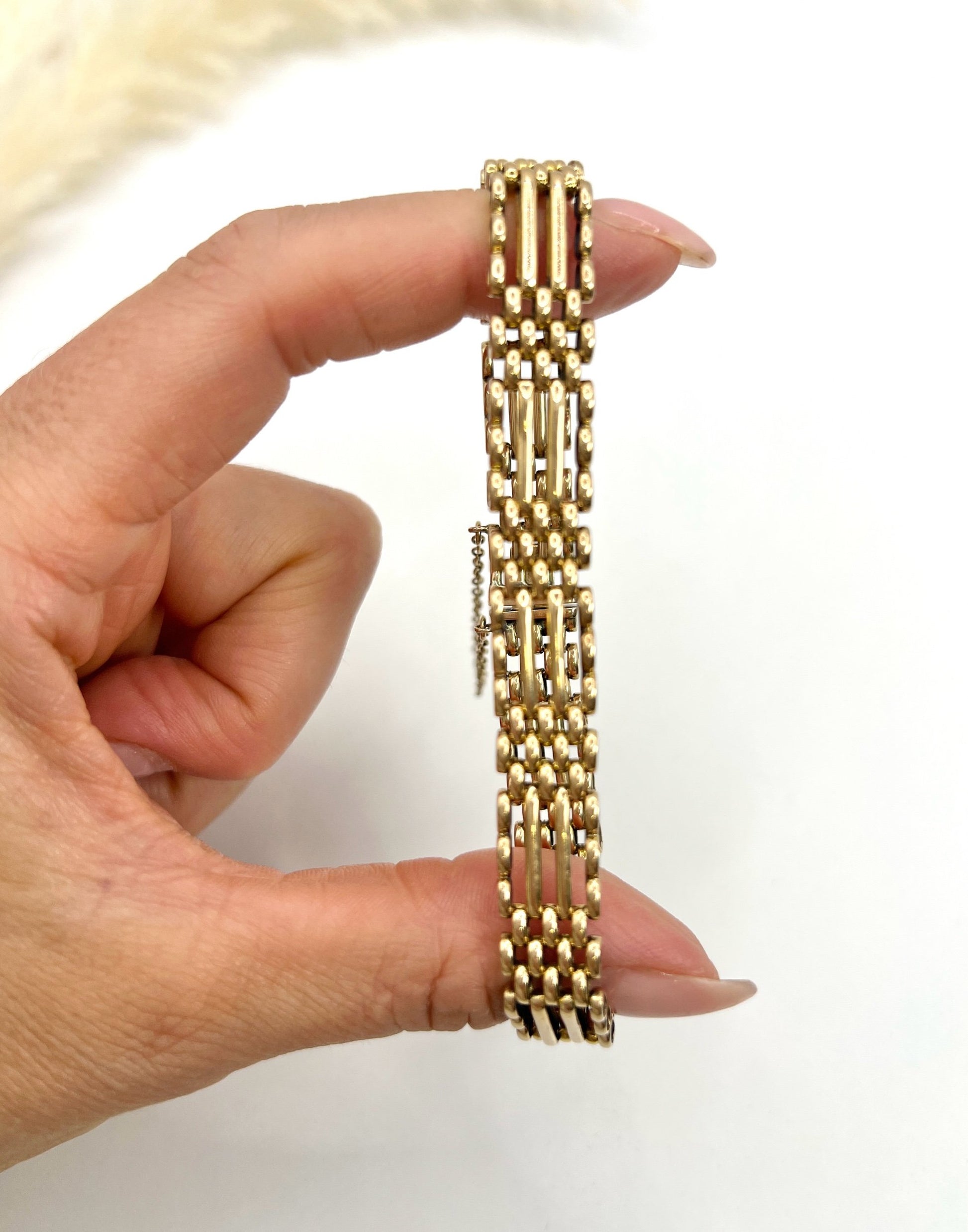 A yellow gold gate bracelet, held in a hand