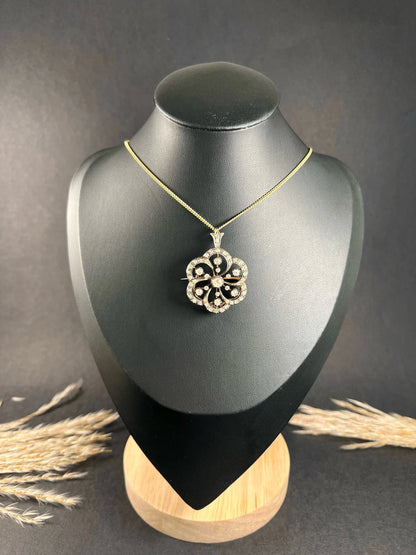 A floral design diamond set pendant/brooch on a gold chain modelled on a black jewellery bust