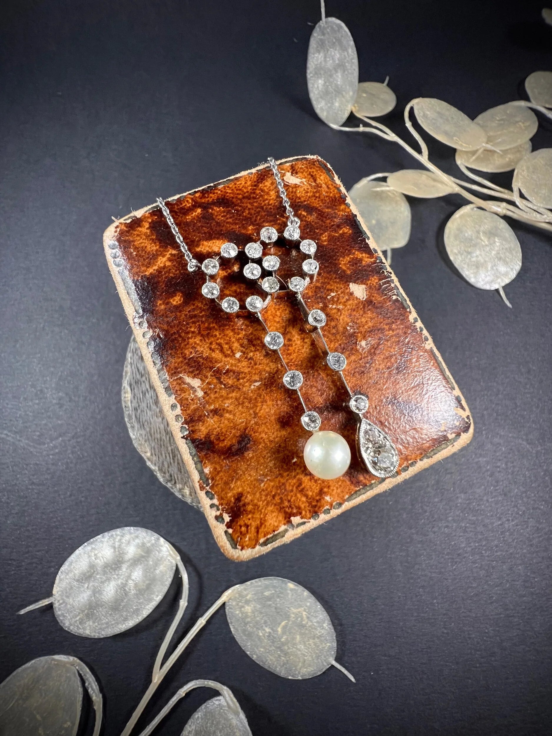 An antique diamond and pearl double drop pendant necklace, on an antique box