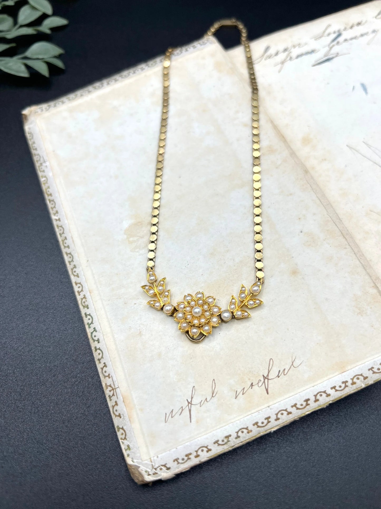 A yellow gold pearl floral necklace with integrated chain