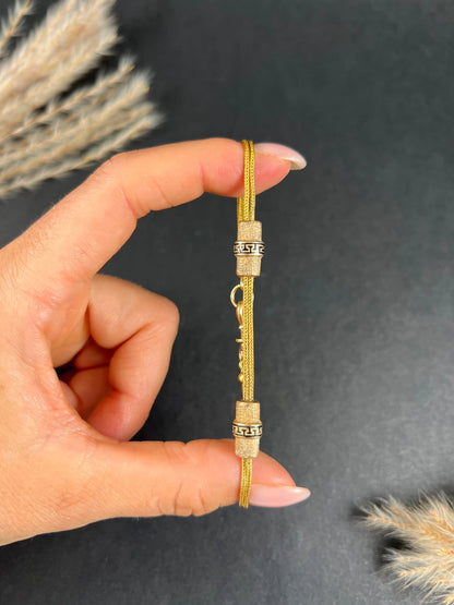 A yellow gold double row bracelet with black enamel tubular beads, held in a hand