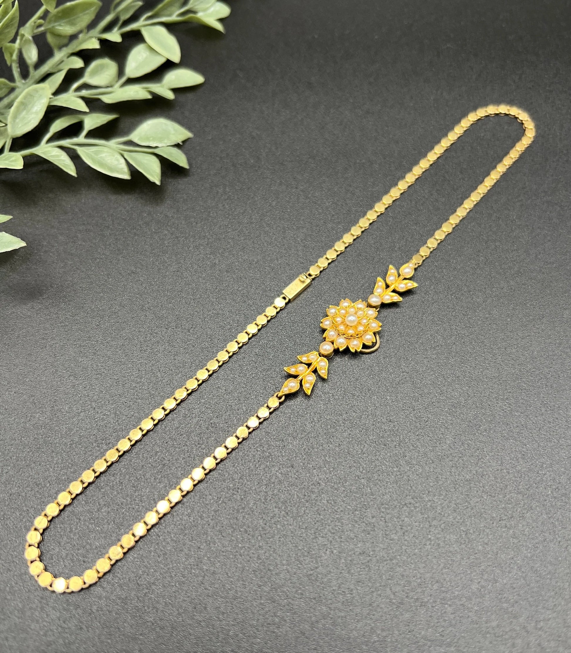 A yellow gold pearl floral necklace with integrated chain