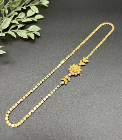A yellow gold pearl floral necklace with integrated chain