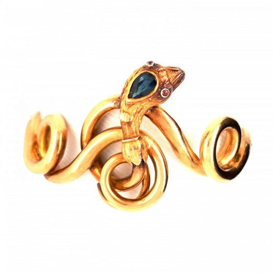 Antique Victorian Sapphire, Ruby and Gold Snake Bangle Bracelet; pear shape sapphire and cabochon ruby eyes set in a textured gold head with foliate design, on 18ct gold coiled body with a hinge and box and tongue clasp, Circa 1875