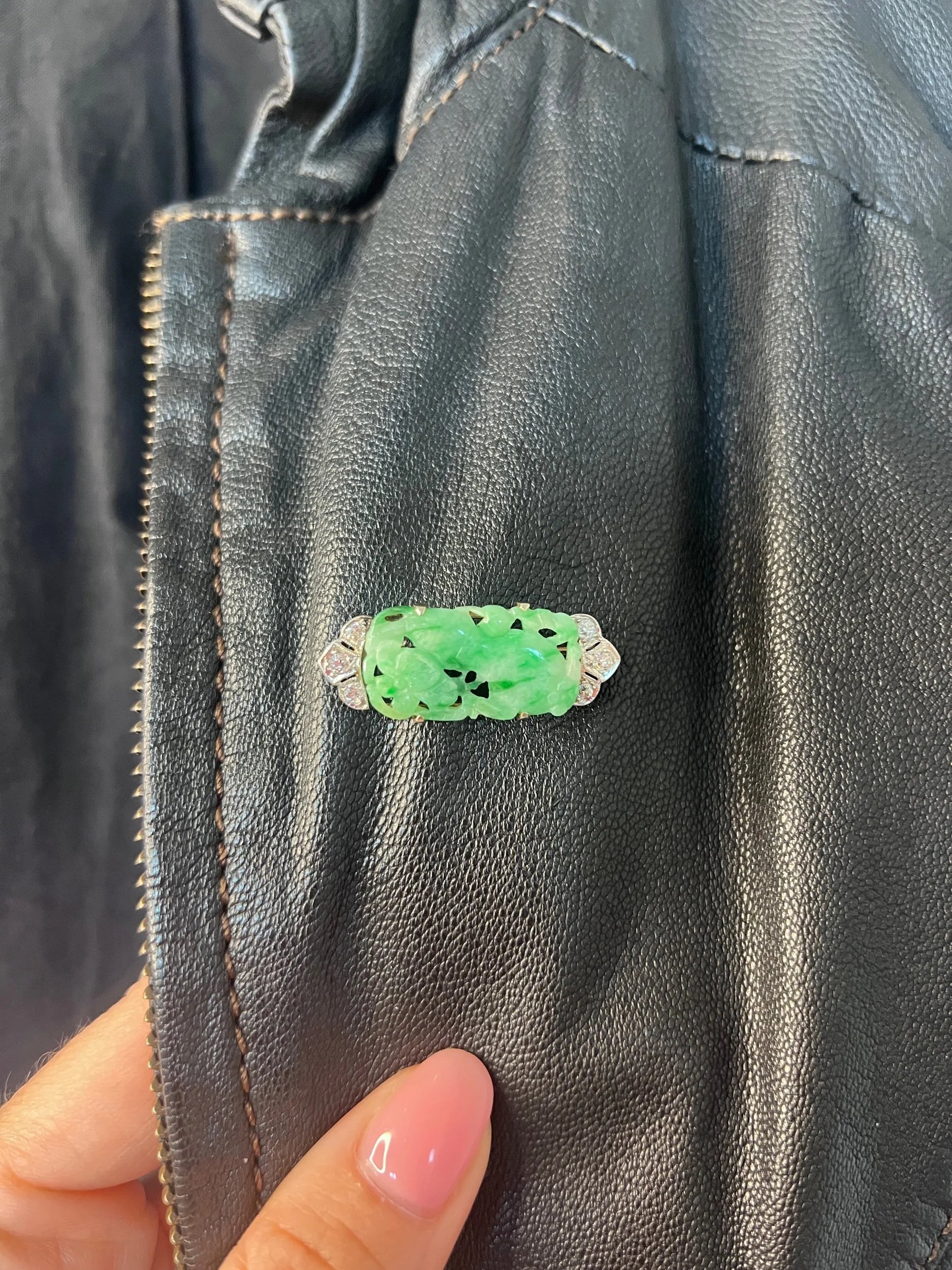 A carved green jade and diamond brooch in white gold, modelled on a black jacket