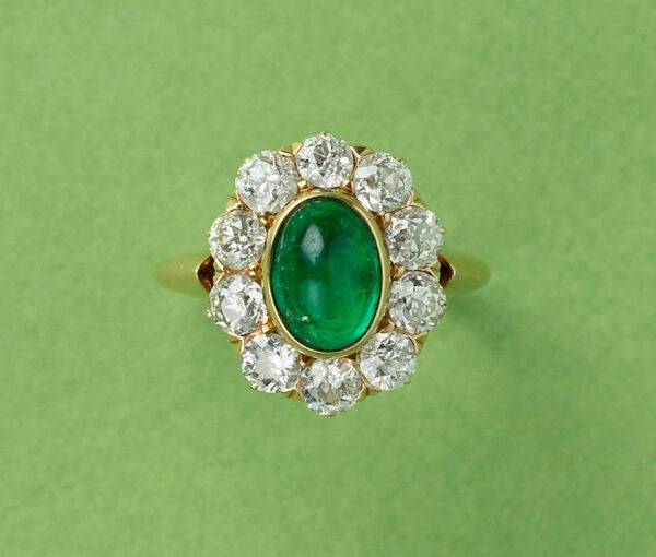 Antique Edwardian Cabochon Emerald and Old Cut Diamond Cluster Ring; 1.54ct oval cabochon cut emerald surrounded by ten old cut diamonds totalling 1.50cts, in 18ct yellow gold. American, Circa 1910