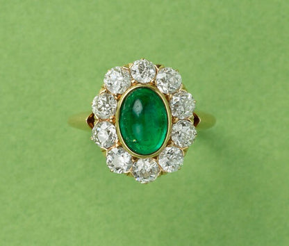 Antique Edwardian Cabochon Emerald and Old Cut Diamond Cluster Ring; 1.54ct oval cabochon cut emerald surrounded by ten old cut diamonds totalling 1.50cts, in 18ct yellow gold. American, Circa 1910