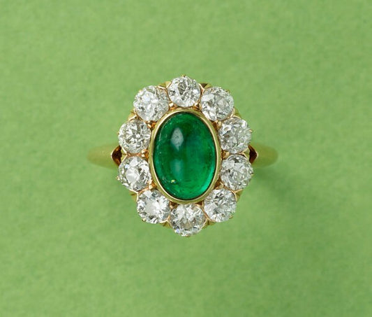 Antique Edwardian Cabochon Emerald and Old Cut Diamond Cluster Ring; 1.54ct oval cabochon cut emerald surrounded by ten old cut diamonds totalling 1.50cts, in 18ct yellow gold. American, Circa 1910