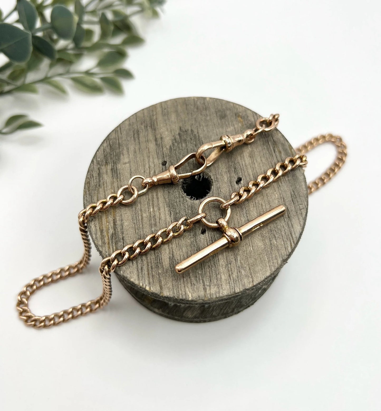 A gold curb link Albert chain, laid on a wooden spool