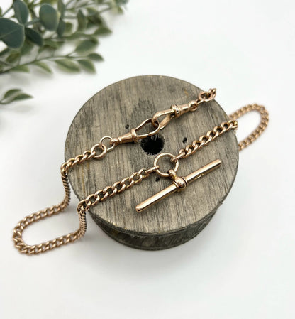 A gold curb link Albert chain, laid on a wooden spool