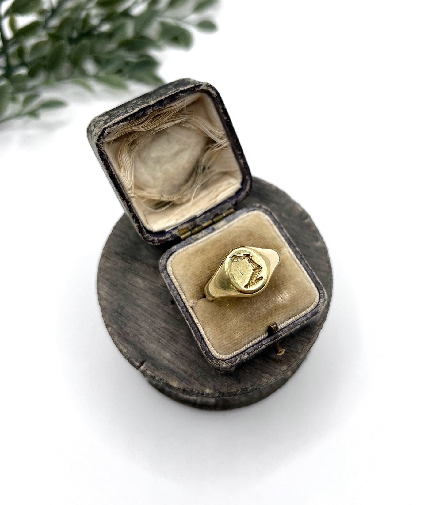 A yellow gold oval signet ring with a seal engraved heraldic crest, in an antique ring box