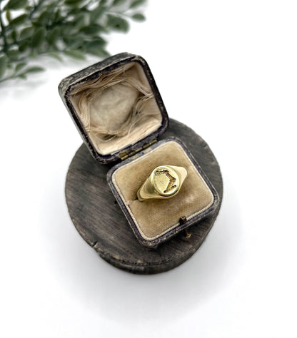 A yellow gold oval signet ring with a seal engraved heraldic crest, in an antique ring box