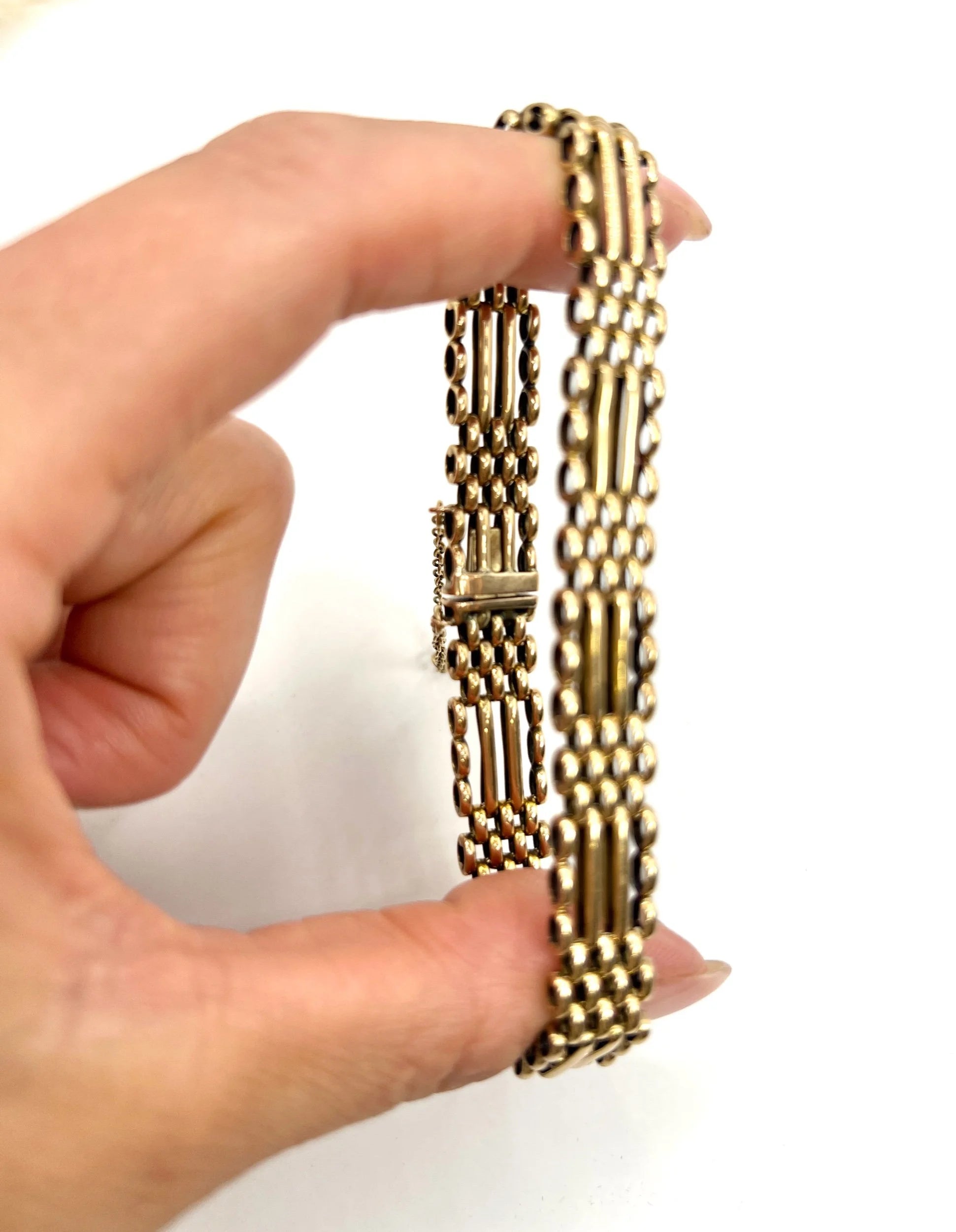 A yellow gold gate bracelet, held in a hand