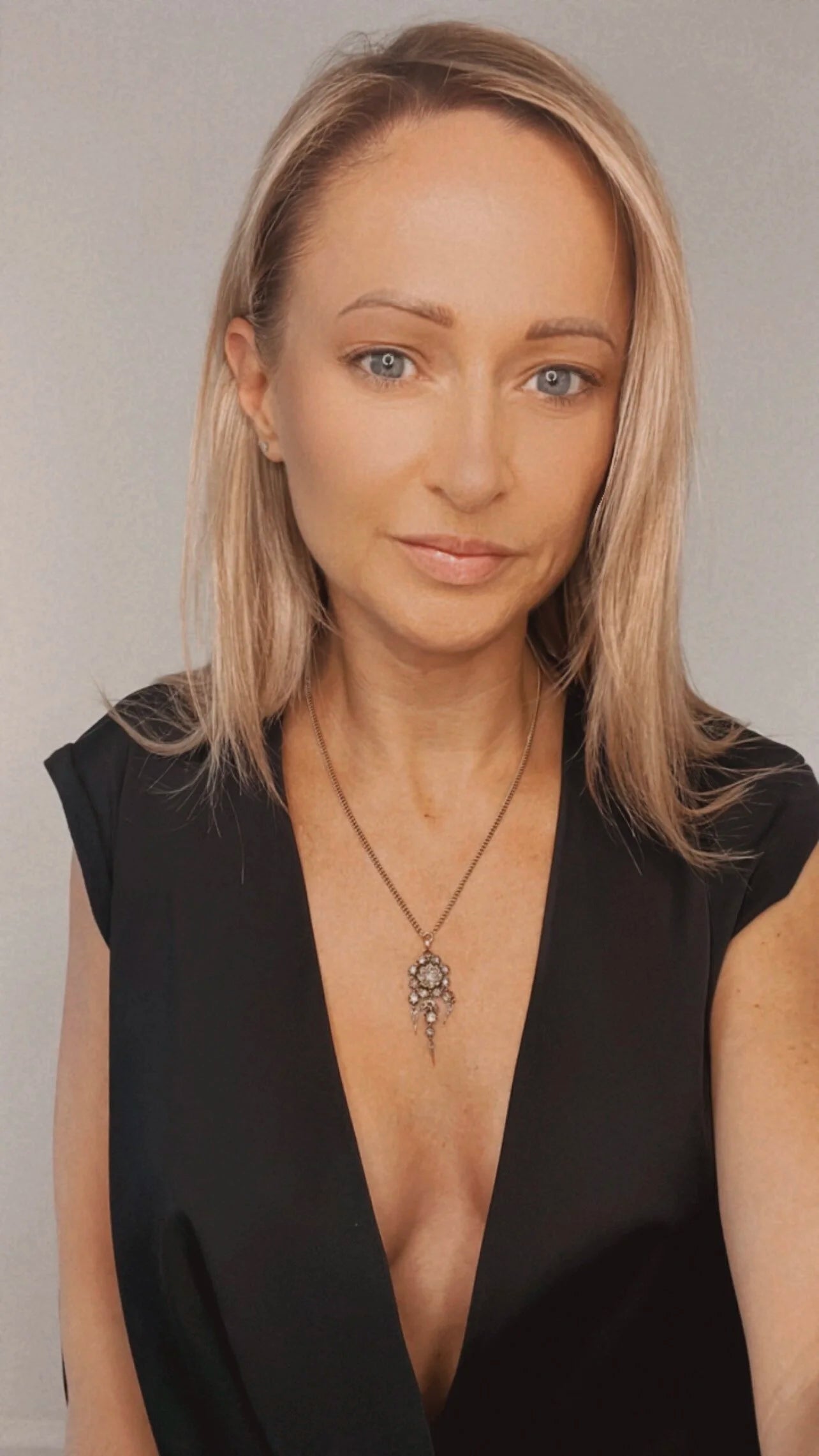 A yellow gold pendant with old cut diamonds, with a gold chain, modelled by a woman wearing a black top