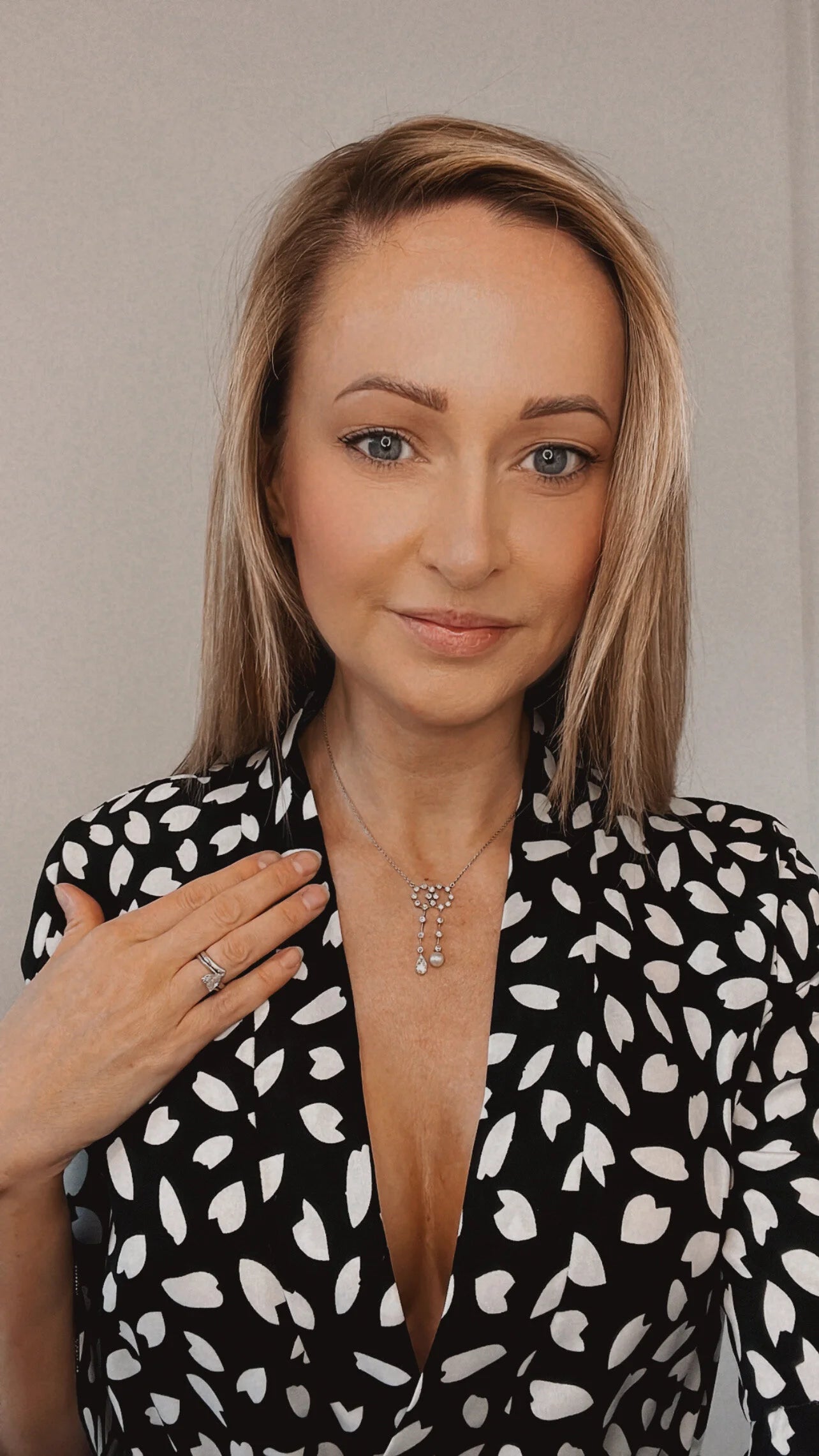 An antique diamond and pearl double drop pendant necklace, modelled by a woman wearing a black and white patterned top