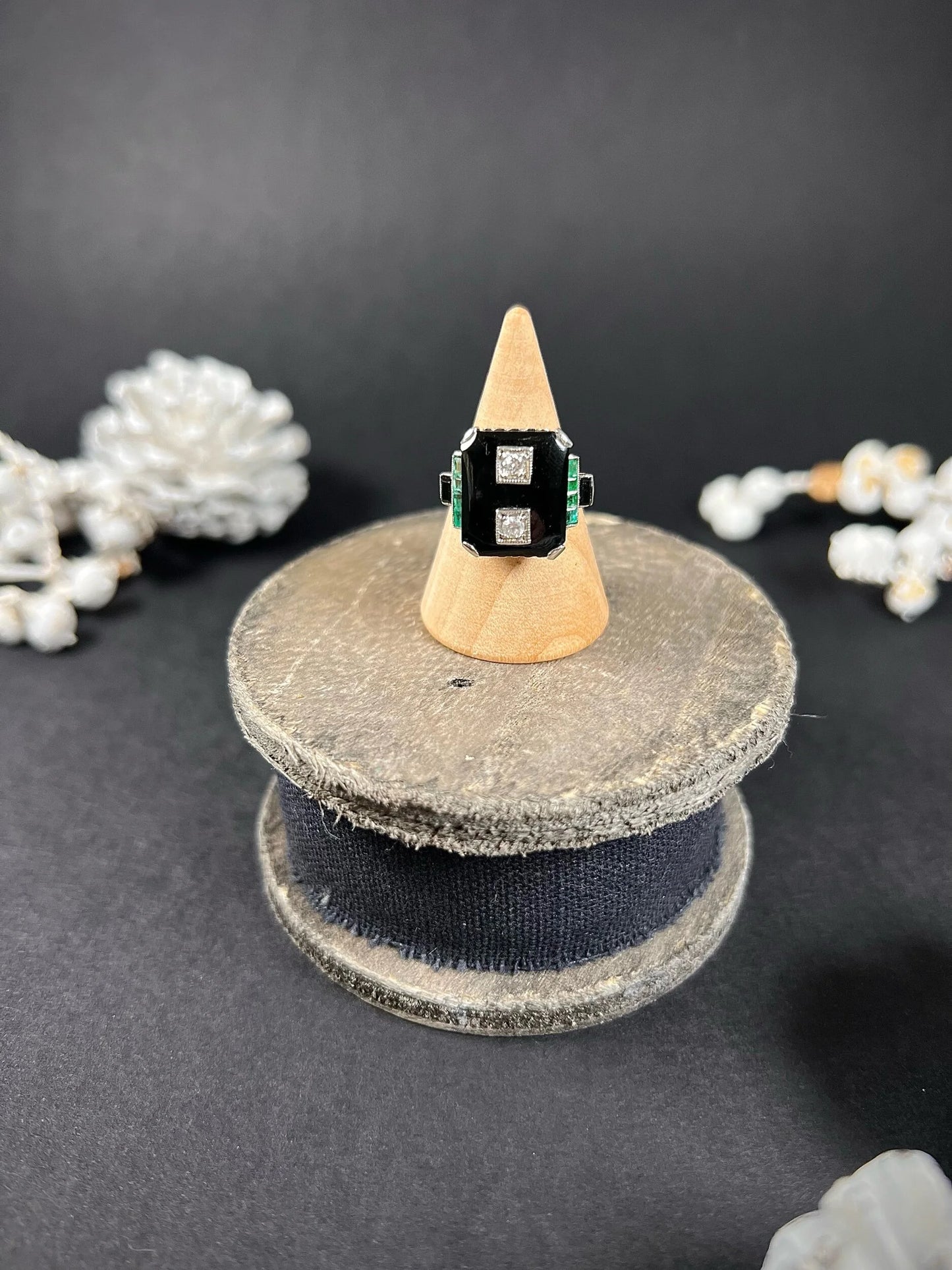 A geometric black onyx ring with diamonds and emeralds in white gold, on a ring cone