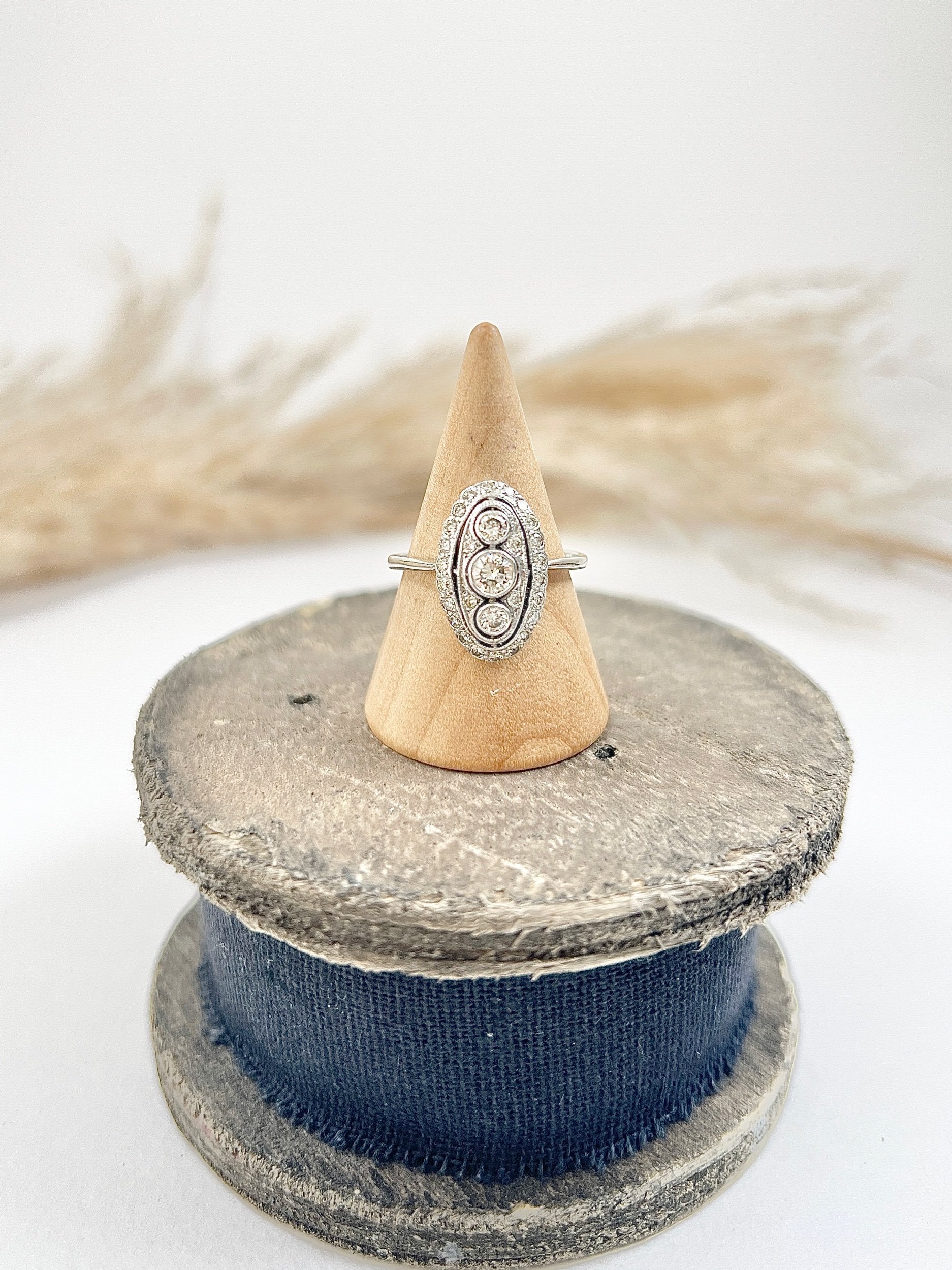 Antique 18 Carat White Gold Three Stone Diamond Oval Halo Ring, Circa 1910