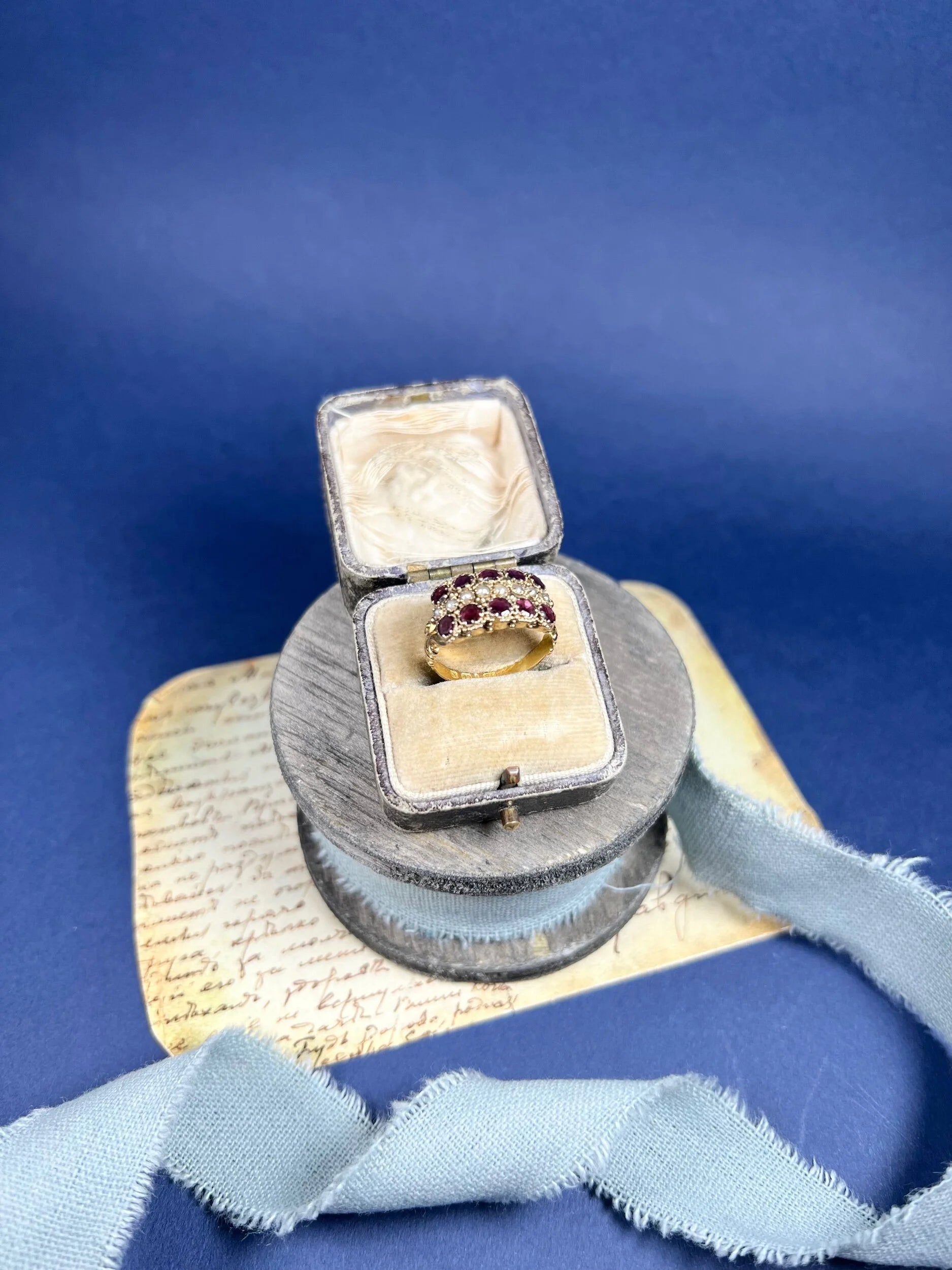A yellow gold triple row ring with garnets and seed pearls, in a box