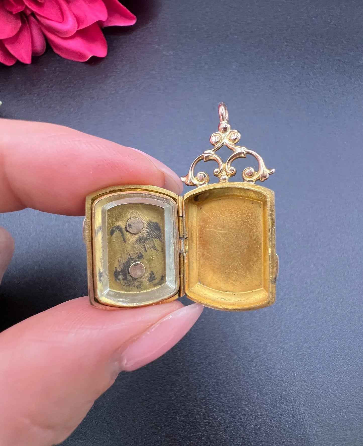 A yellow gold ornate locket, open, held in a hand