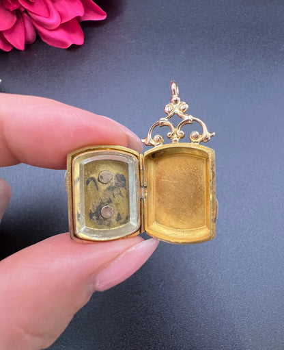 A yellow gold ornate locket, open, held in a hand