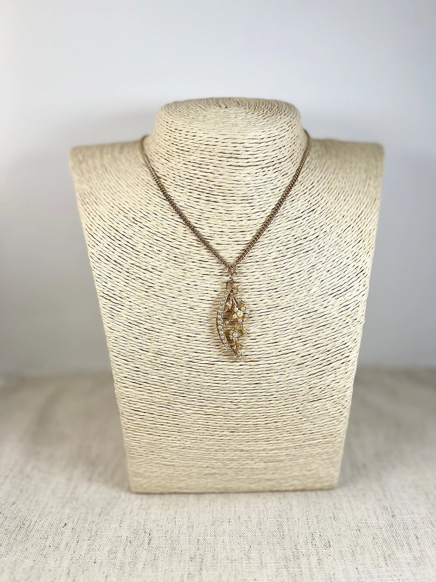 A yellow gold floral crescent pendant with pearls, with a chain