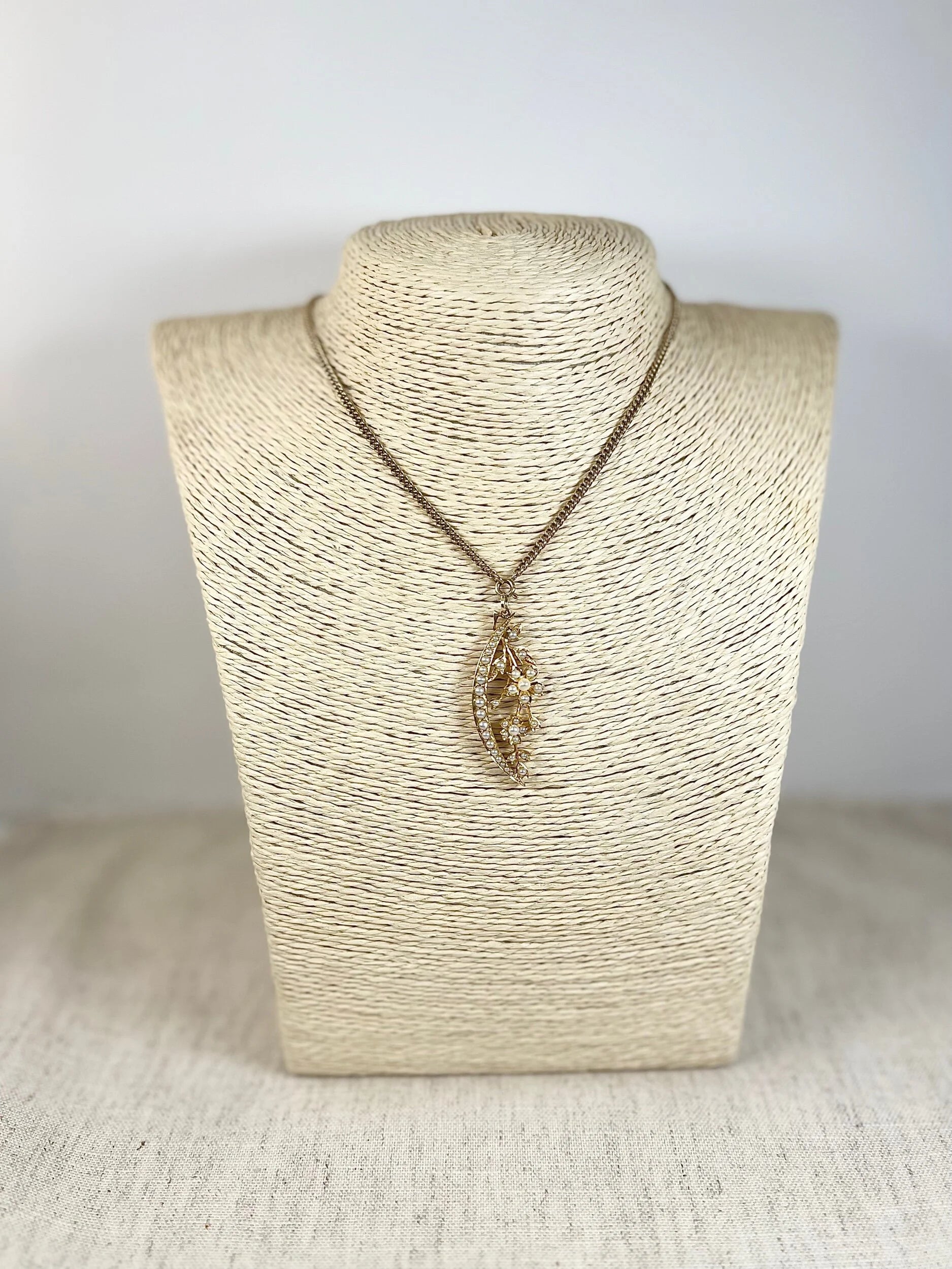 A yellow gold floral crescent pendant with pearls, with a chain
