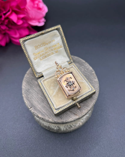 A yellow gold ornate locket with diamond fleur-de-lis detail, in a box