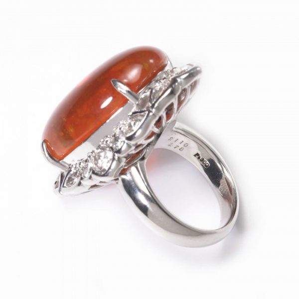 Cabochon Fire Opal and Diamond Cluster Ring in Platinum; central 18.00 carat oval shaped cabochon-cut fire opal, surrounded by 2.40cts brilliant and pear-cut diamonds