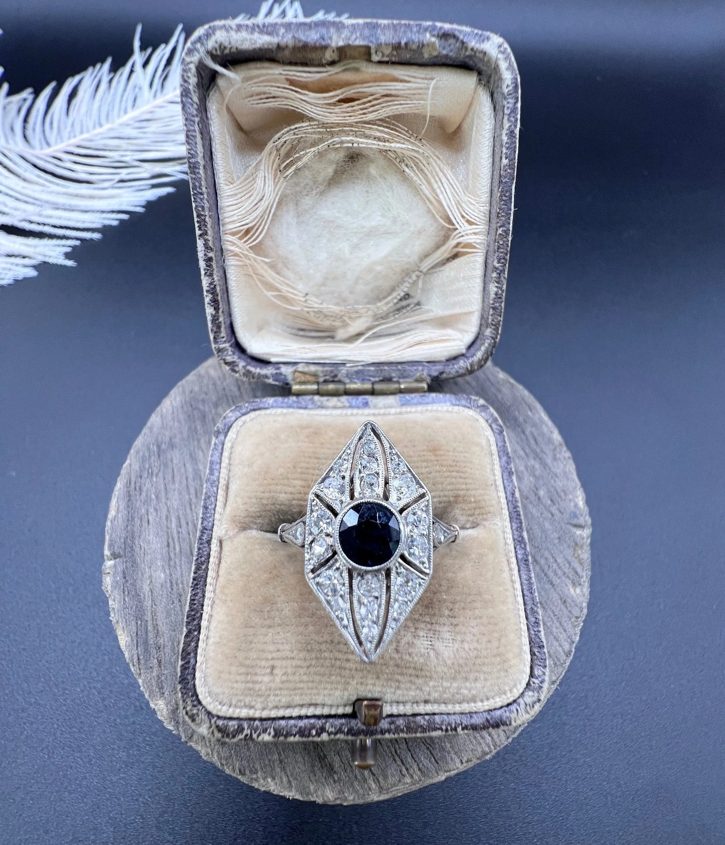 A navette shaped cluster cocktail ring with a sapphire centre surrounded by diamonds, in platinum, in an antique ring box