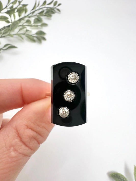 A black onyx and three stone diamond plaque ring in gold