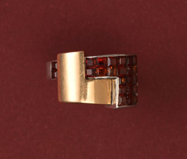 Art Deco Garnet Set Ring; geometrical construct in 18ct gold and platinum, set with 3.60cts square-cut blind-set hessonite garnets. France, Numbered 32827. 