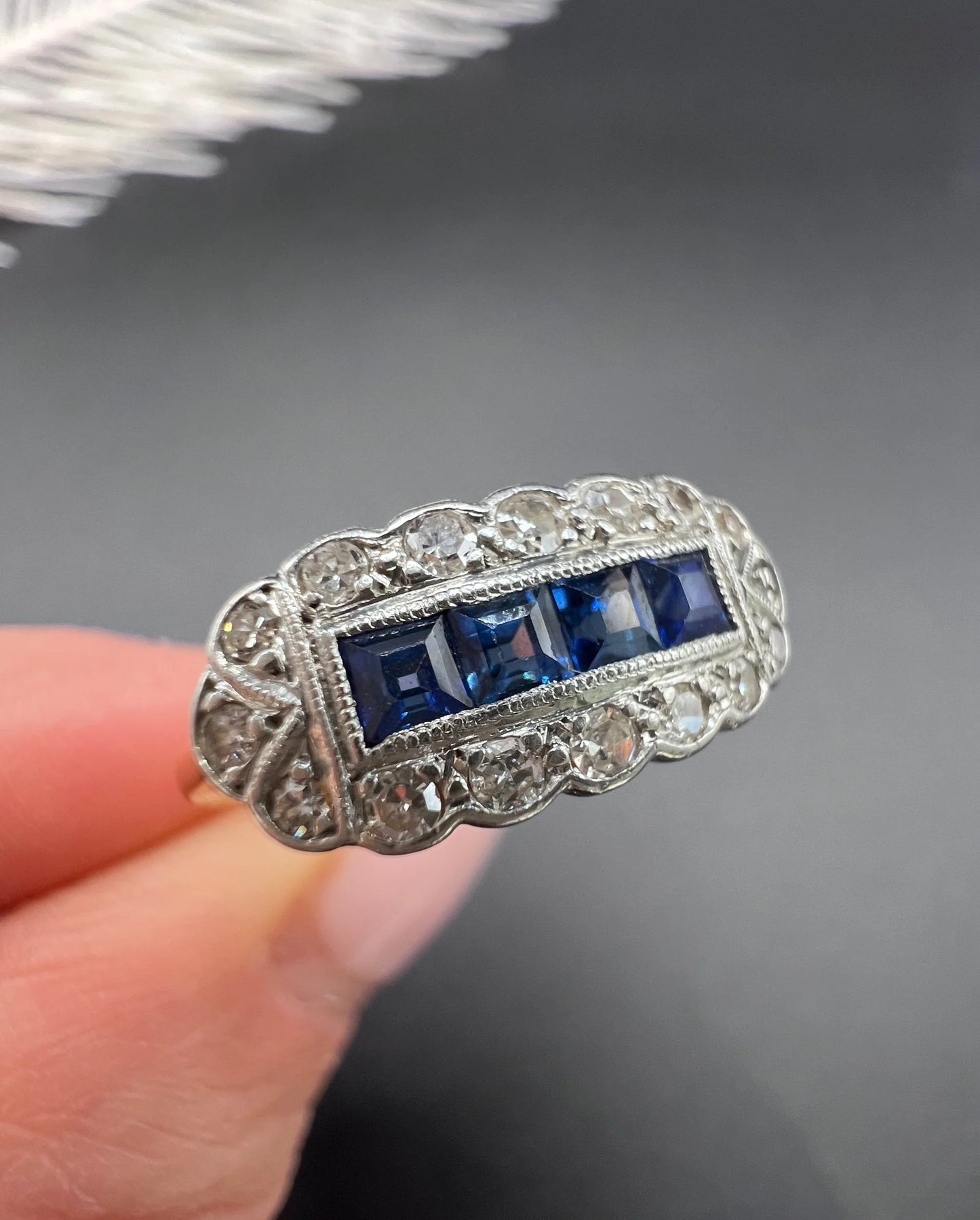 A sapphire and diamond elongated cluster ring in platinum and yellow gold, held in a hand