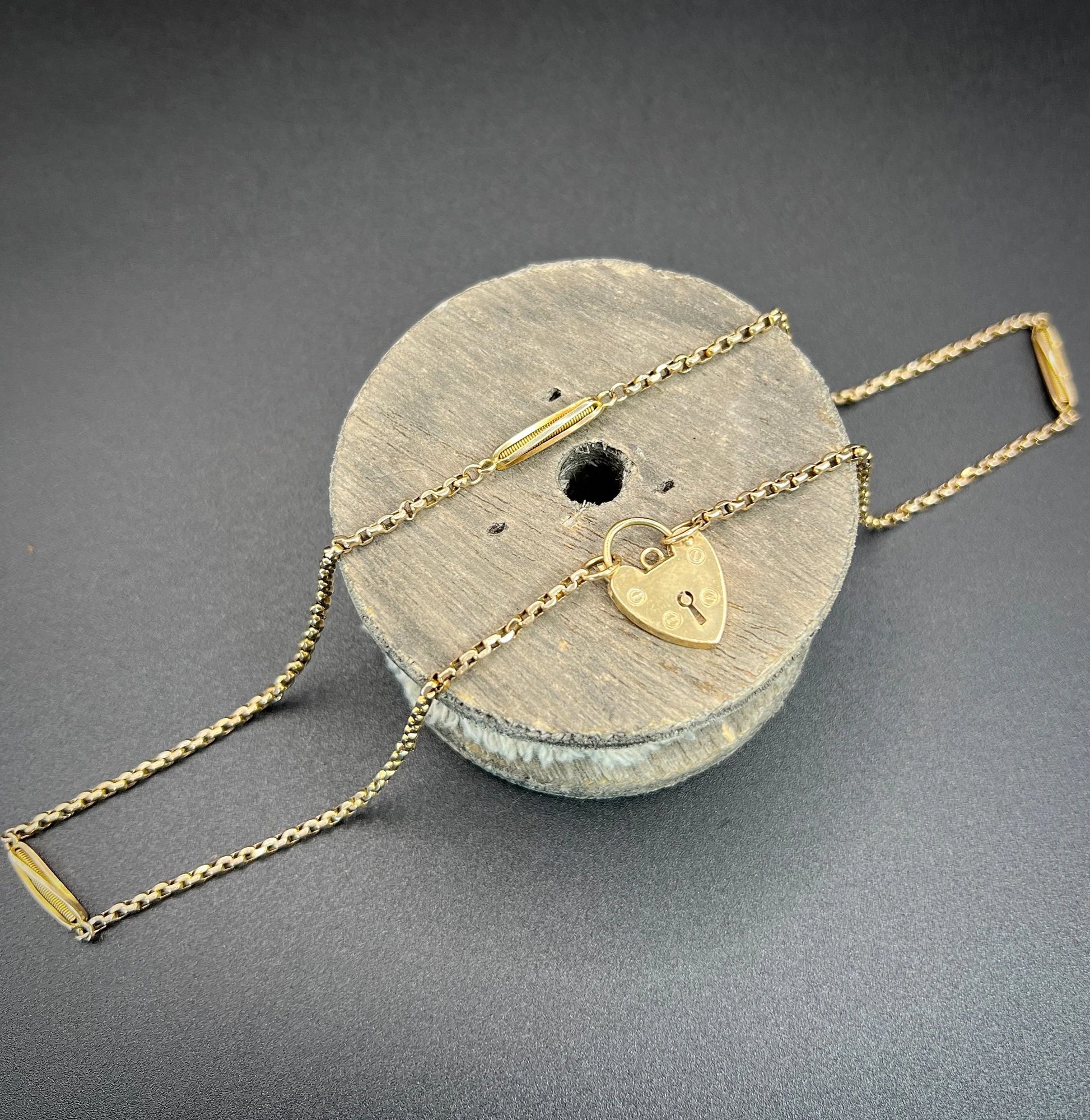 A yellow gold fancy link chain with a heart padlock