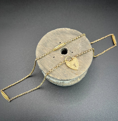 A yellow gold fancy link chain with a heart padlock