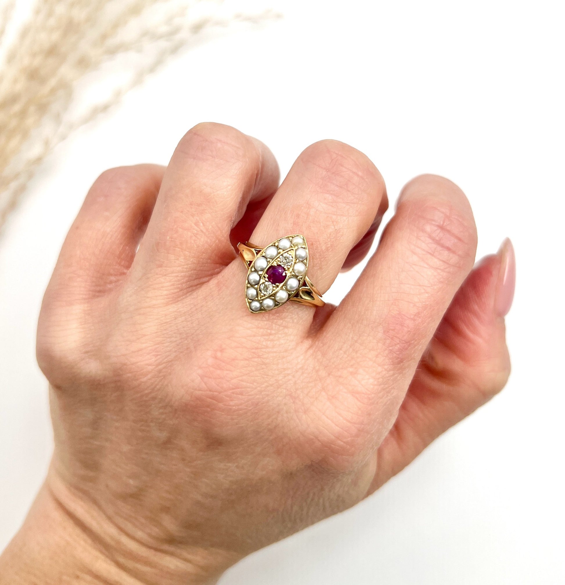 A navette shaped pearl, diamond and ruby cluster ring in yellow gold, modelled on a hand