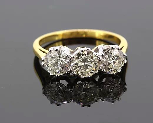 Three Stone Diamond Ring; A classic diamond trilogy ring featuring three round brilliant-cut diamonds totaling 2.06 carats, claw-set, 18ct yellow gold band.