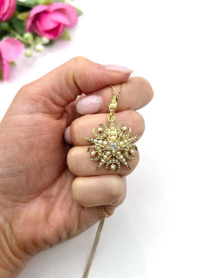 A yellow gold star and crescent brooch/pendant with pearls and a diamond centre, with a chain, held in a hand
