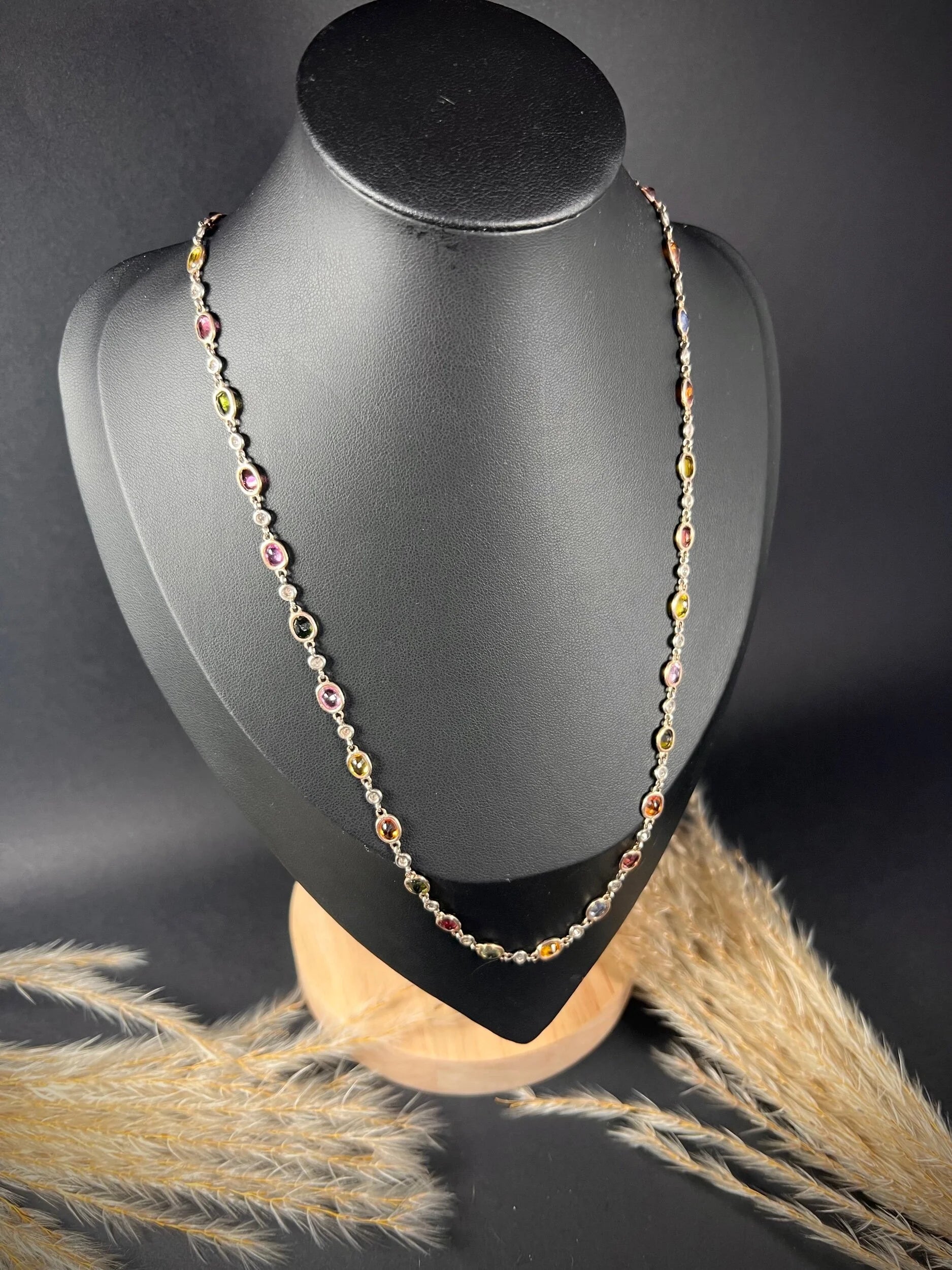 A coloured sapphire and diamond set necklace in platinum and gold, modelled on a black jewellery bust