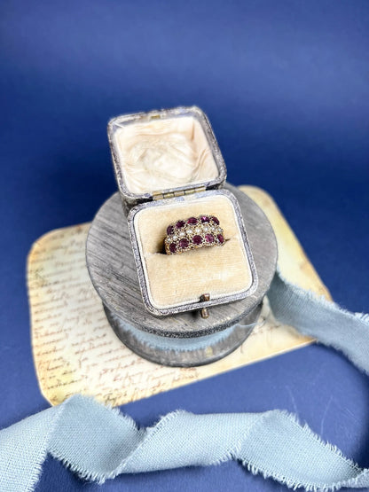 A yellow gold triple row ring with garnets and seed pearls, in a box