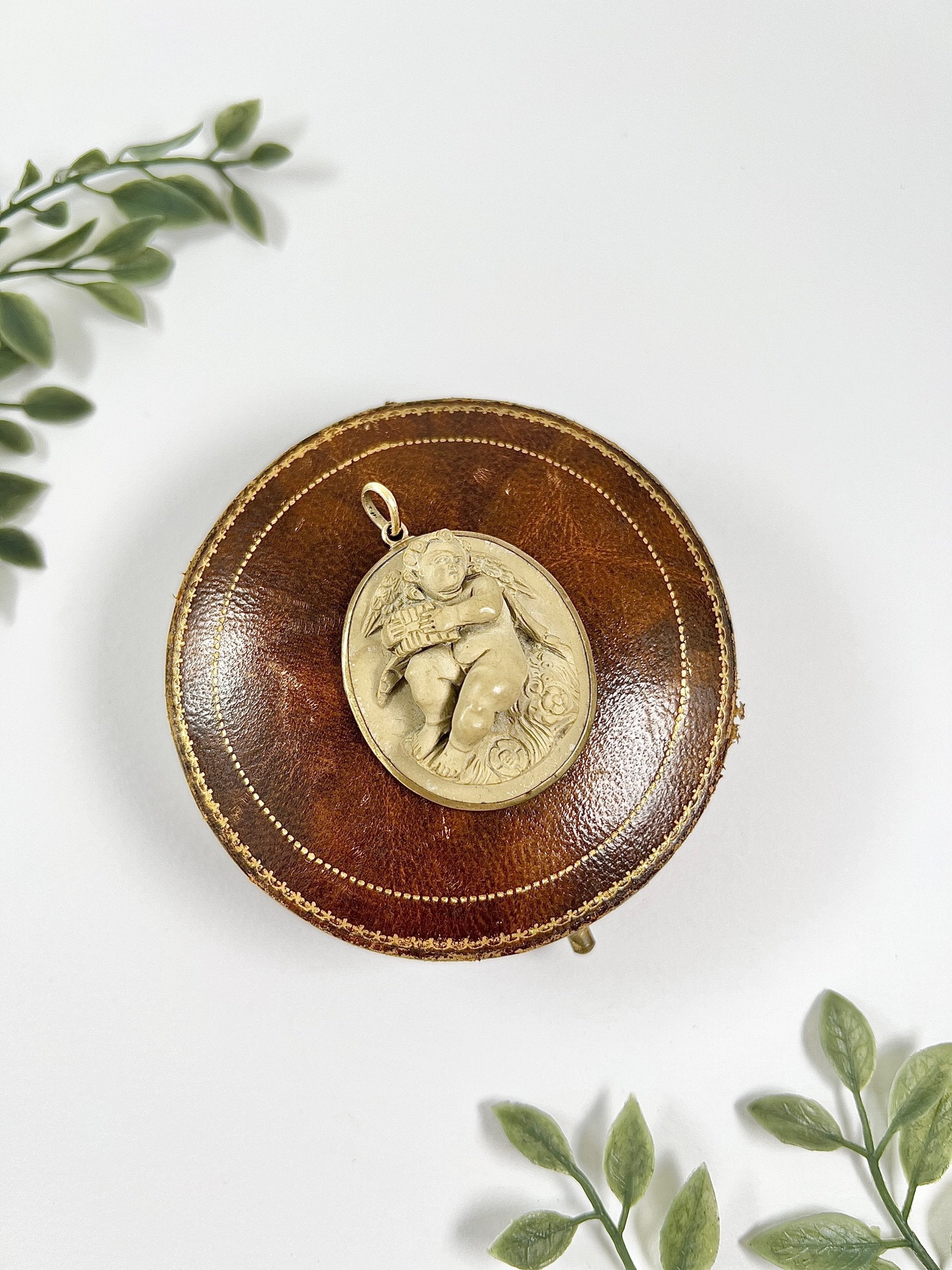 An oval cherub lava cameo pendant in yellow gold