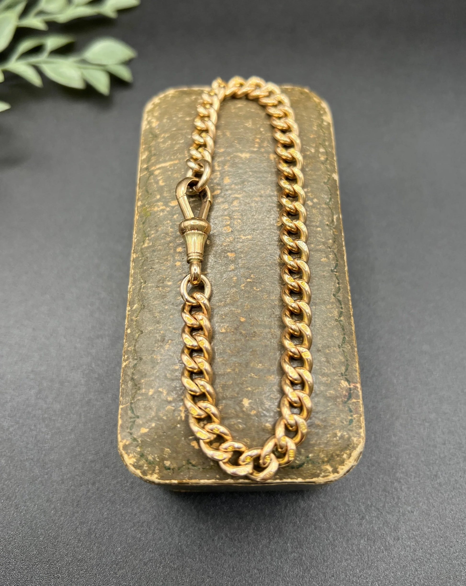 A gold curb link bracelet with a lobster claw clasp