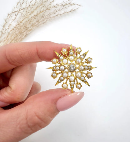 A star-shaped pearl and diamond brooch/pendant in yellow gold, held in a hand