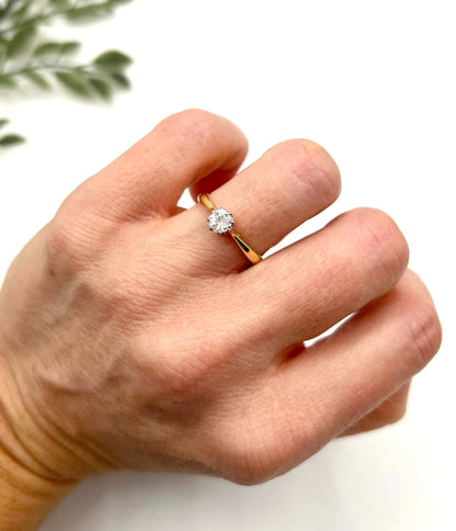 A single stone brilliant cut diamond ring claw set in platinum and yellow gold, modelled on a hand