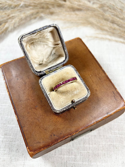 A yellow gold ruby channel set eternity band, in an antique ring box