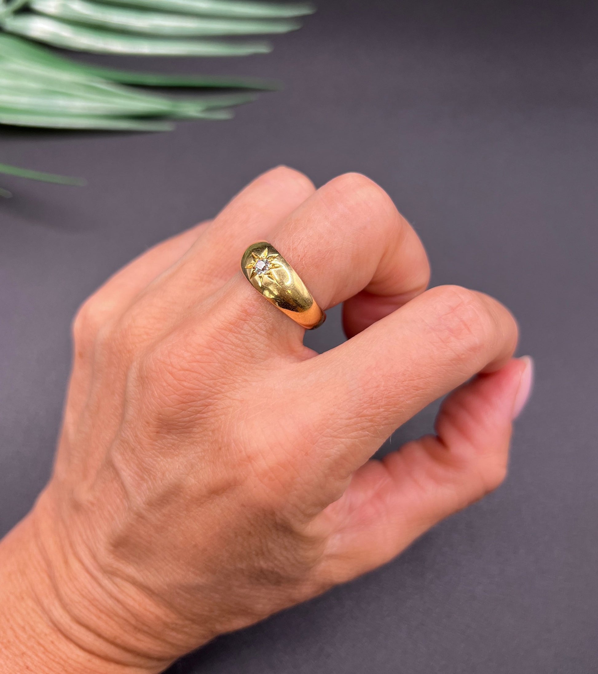 A single stone old cut diamond gypsy band ring in yellow gold, modelled on a hand