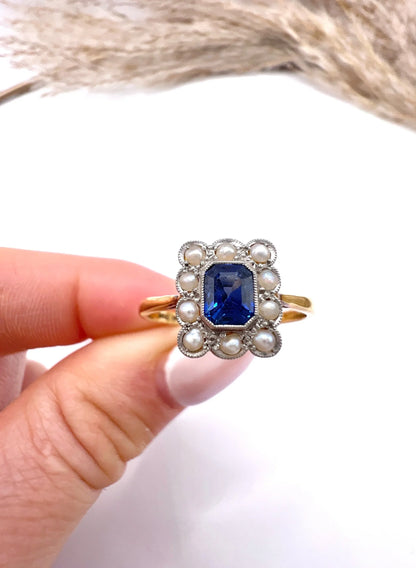 A sapphire and pearl cluster ring in yellow gold and platinum, held in a hand