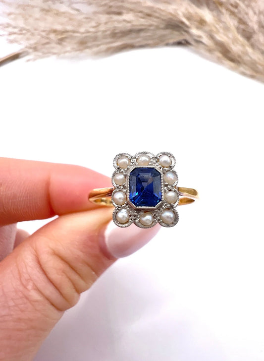 A sapphire and pearl cluster ring in yellow gold and platinum, held in a hand