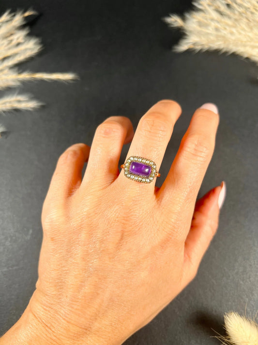A cabochon amethyst and pearl halo cluster ring in gold, modelled on a hand