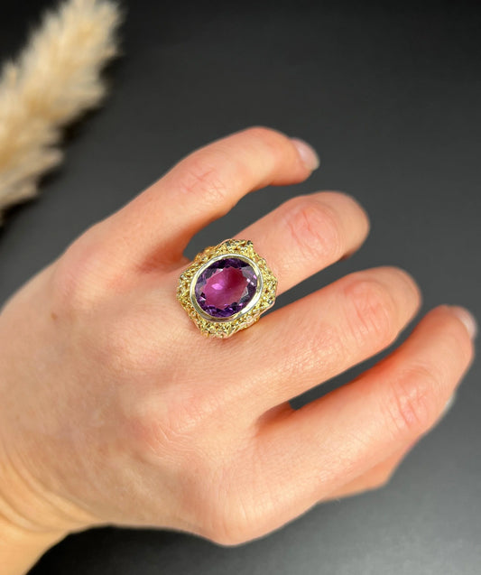 A yellow and white gold ornate solitaire ring with an oval amethyst, modelled on a hand