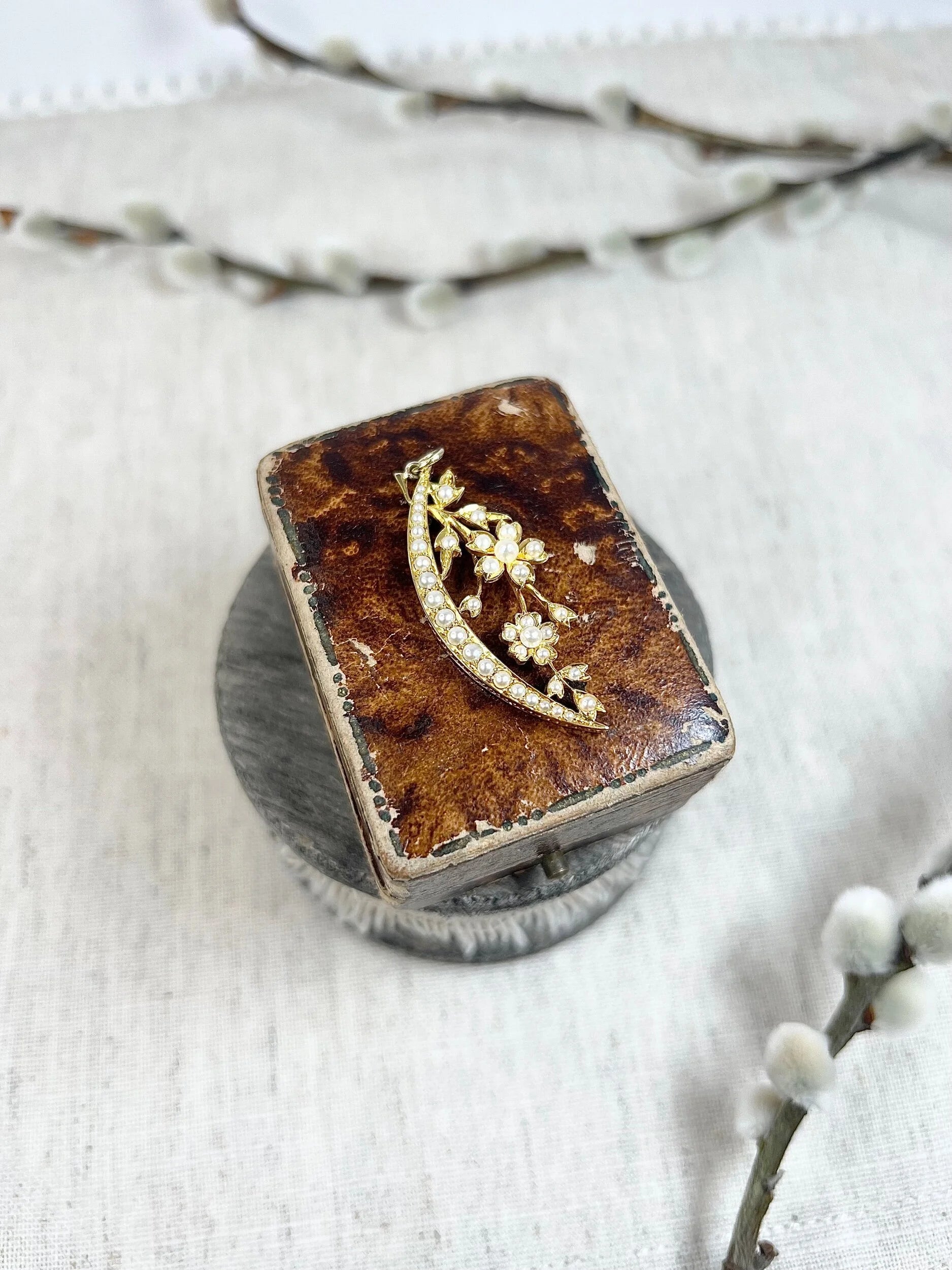 A yellow gold floral crescent pendant with pearls